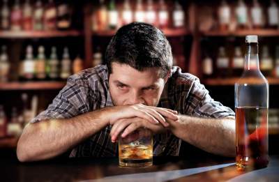 Man drinking alcohol alone at bar due to high stress work