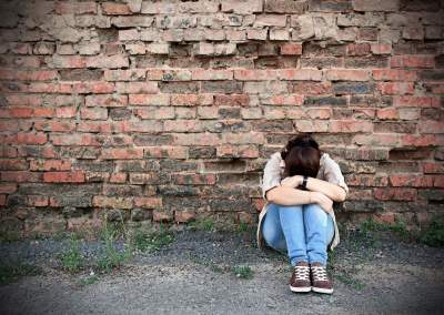 Girl feeling depressed sad and alone in front of brick wall