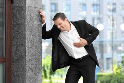 Man with high stress work grabbing chest worried he is having heart attack